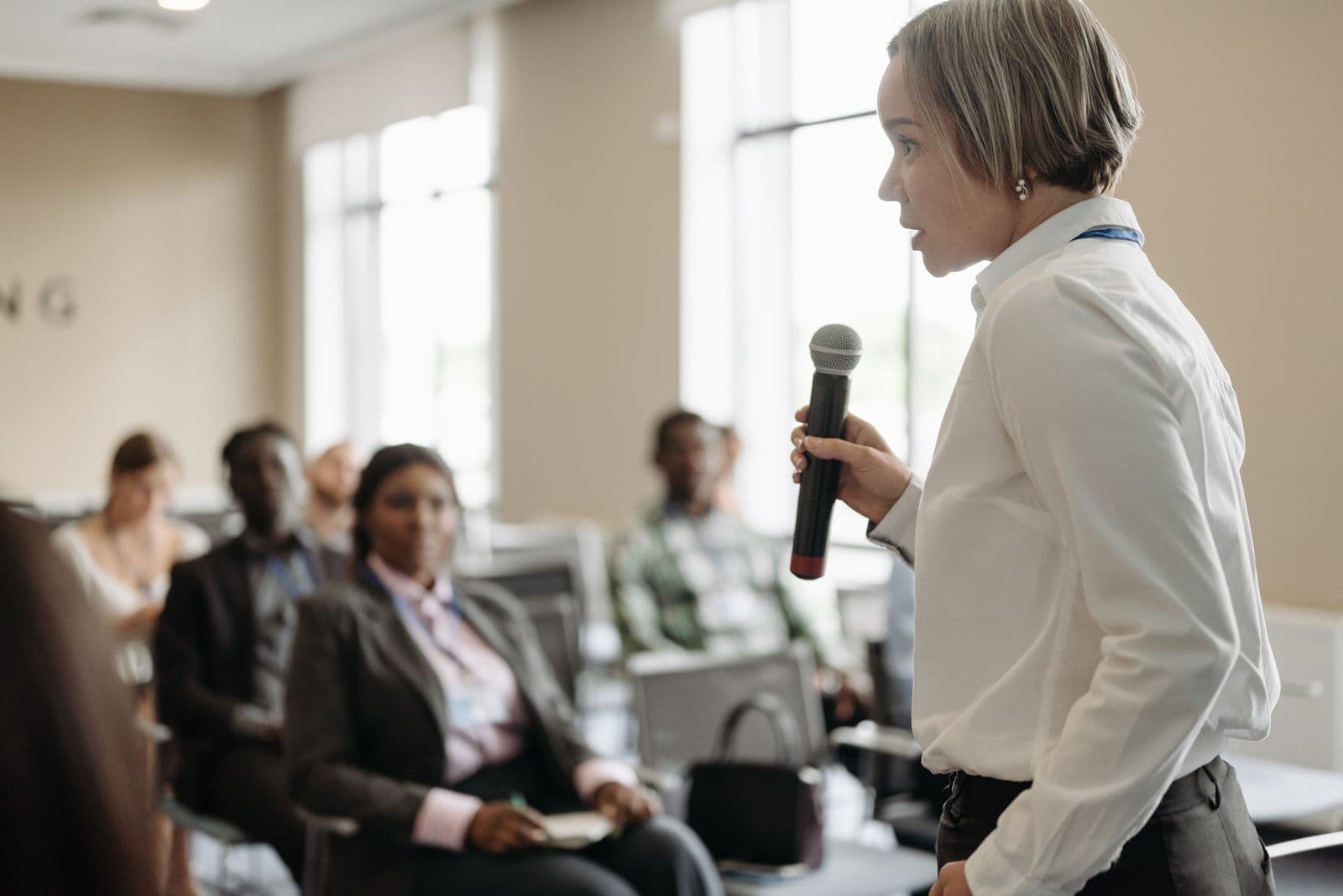 Side view of a businesswoman holding a microphone while addressing a room