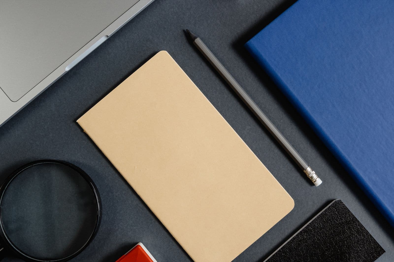 Office stationery arranged in a minimalist flat lay on a dark surface