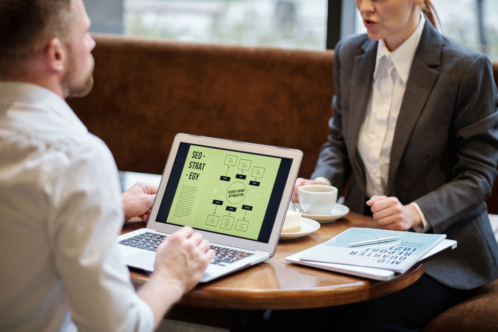 Two colleagues discussing plans across a table in an office