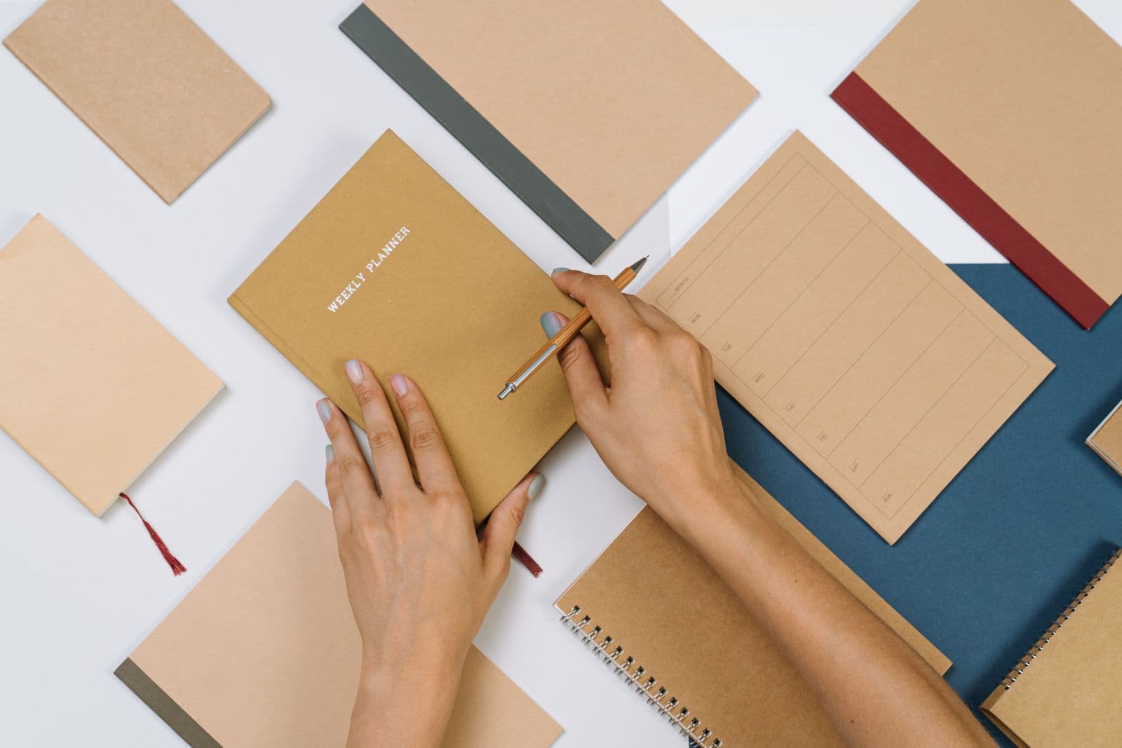 A flat lay of stationery with hands writing in an open planner