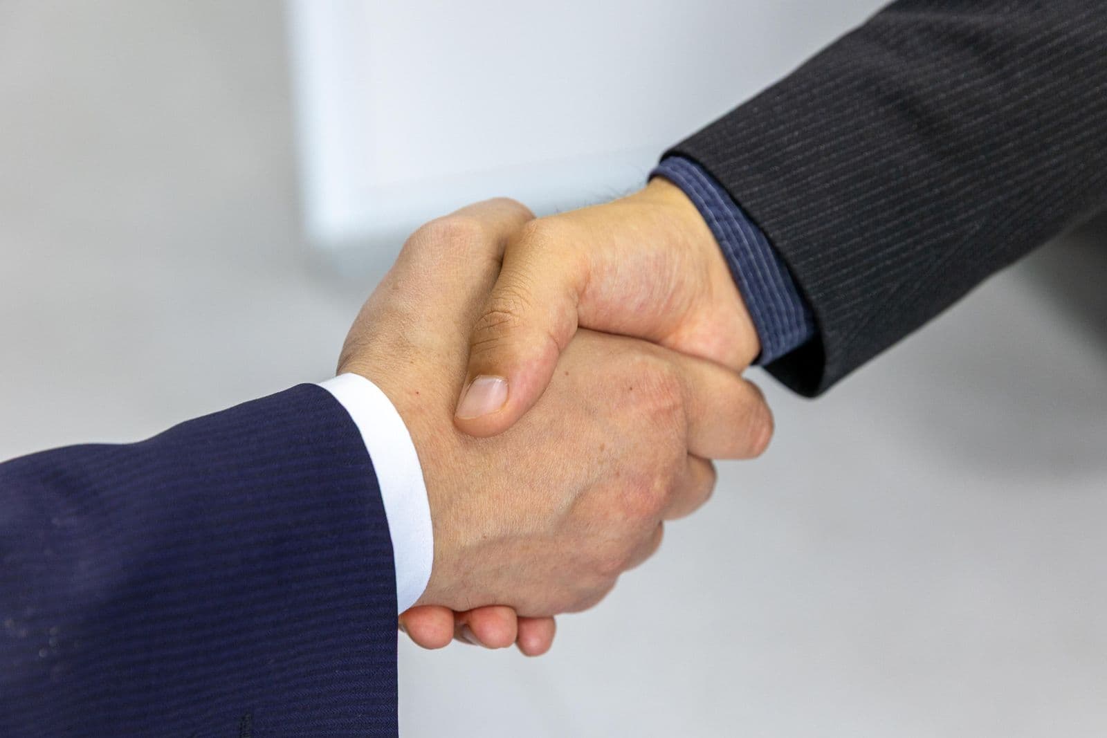 Two professionals shaking hands across a desk after a meeting